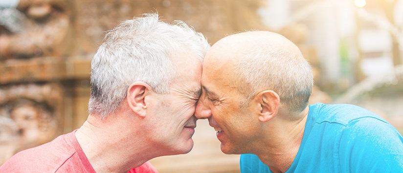 Gay couple at park in New York. They are two men in their early sixties, standing face to face, cuddling and smuggling. Homosexual love concept