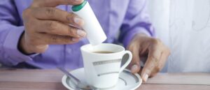 Person using an artificial sweetener in their drink