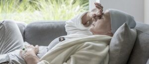 Woman with cancer (in a head scarf) resting on couch, cancer patient