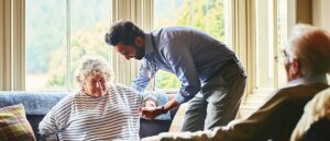 GP helping older woman up from seat, mobility issues