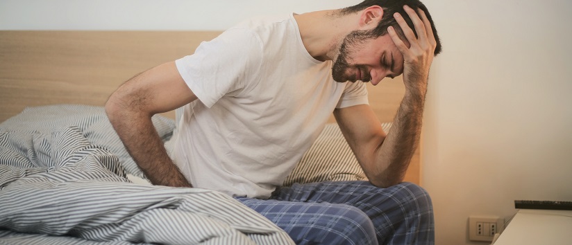 man sat on bed with headache