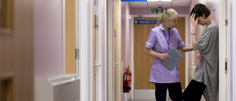 Nurse with a family member in hospital corridor