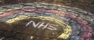 NHS and rainbow written on road with chalk, health and care bill