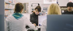 woman at till in pharmacy, buying product from pharmacist, NHS prescription charges
