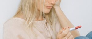 woman looking at pregnancy test, infertility, pregnancy loss