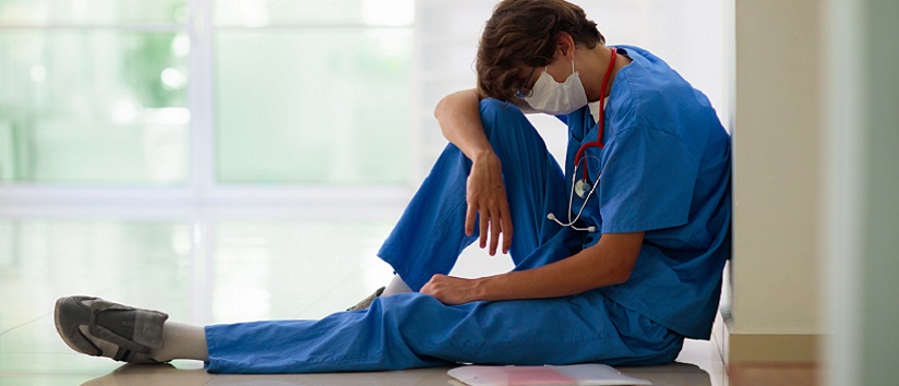 stressed NHS nurse resting head on knees