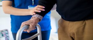 nurse helping man walk with zimmer frame