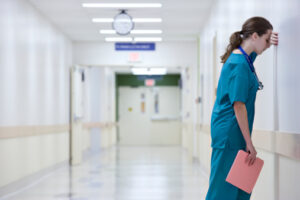 stressed junior doctor resting head on wall