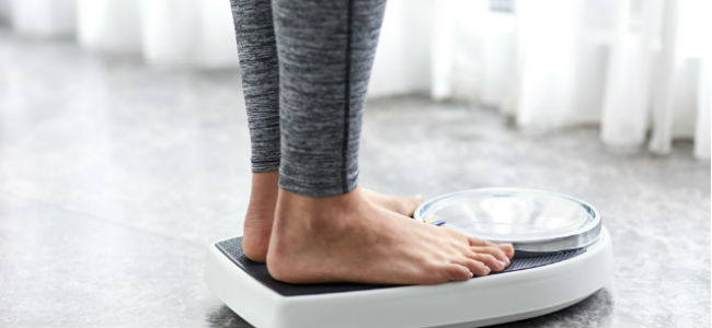 woman standing on scales, eating disorder