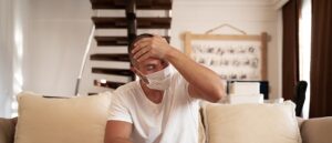 man wearing Covid face mask with hand on head
