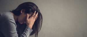 woman with head in her hands, post traumatic stress disorder, mental health, depression