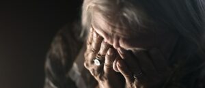 Woman with alzheimers with head in hands, crying. Depression.