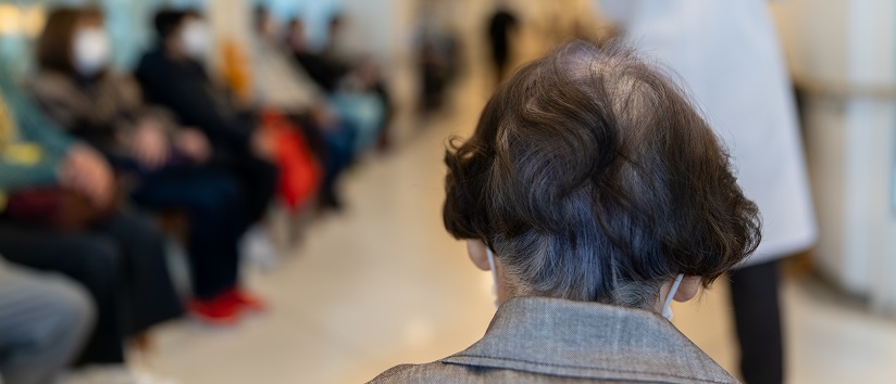 Senior woman wearing face mask in a hospital, waiting room.
