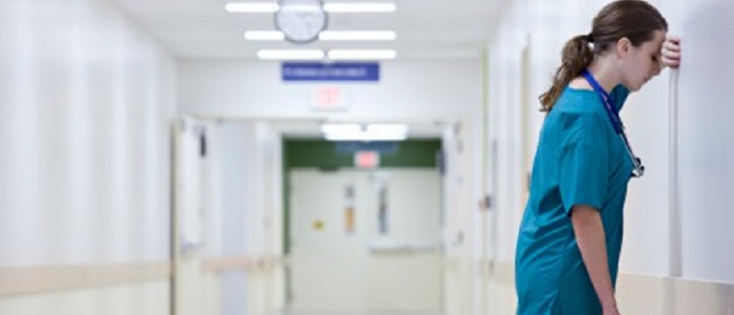 Stressed hospital consultant leaning against wall