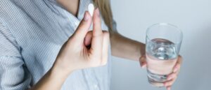 woman taking tablet with glass of water