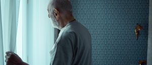 older person looking out window