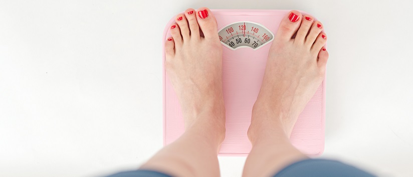 woman stood on scales, eating disorder, BMI