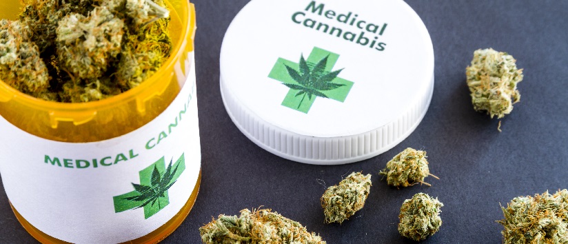 Medical marijuana buds in large prescription bottle with branded cap on black background, medicinal cannabis