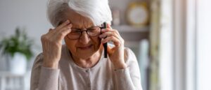 Senior woman feeling pain while consulting doctor on her smart phone