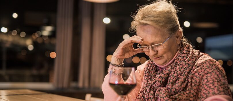 Senior woman with high-risk alcohol misuse drinking wine