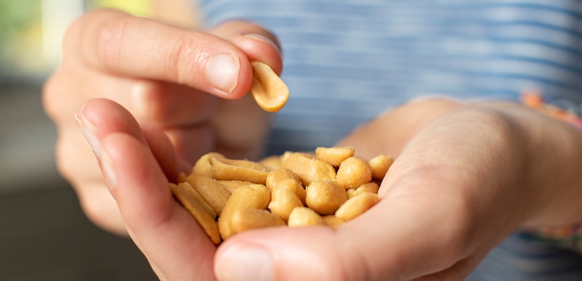 Close Up Of Teenage Girl Eating Handful Of Salted Peanuts